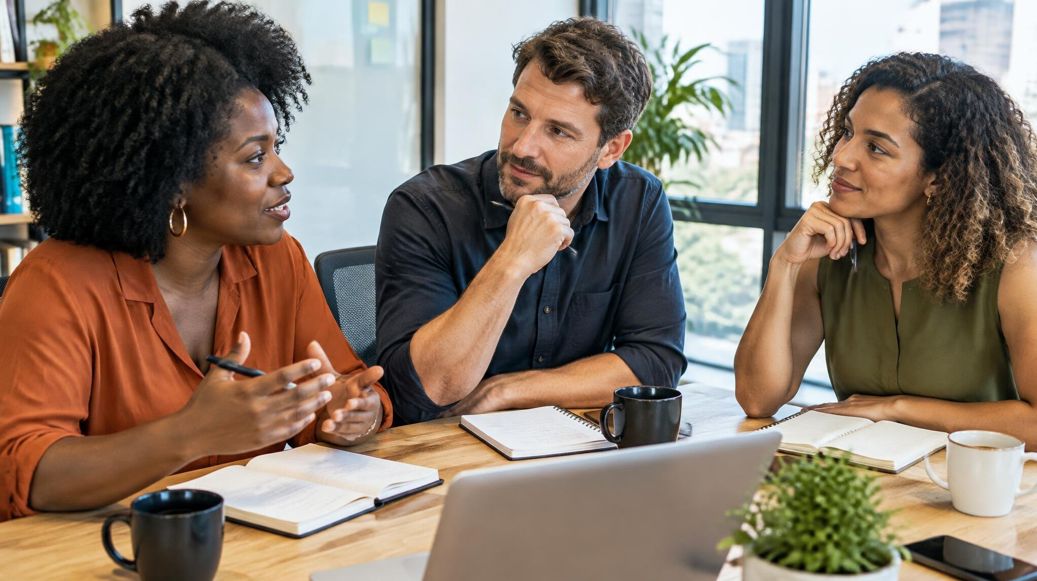 People in a discussion at a meeting table with notebooks