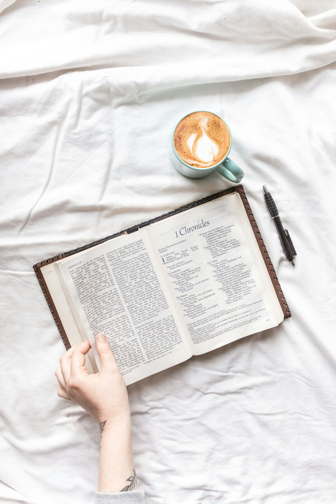 Hand writing in a notebook next to a cup of coffee